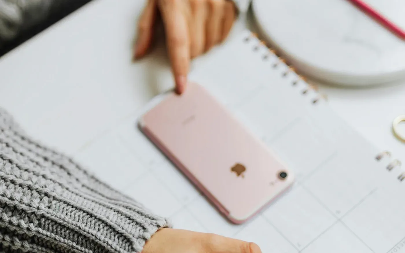 Pessoa a apontar para um calendário menstrual com telemóvel sobre a agenda