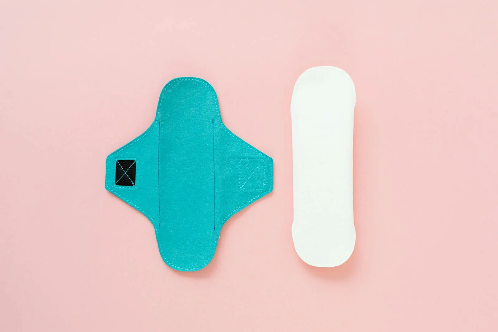 Pensos menstruais reutilizáveis e descartáveis sobre fundo rosa