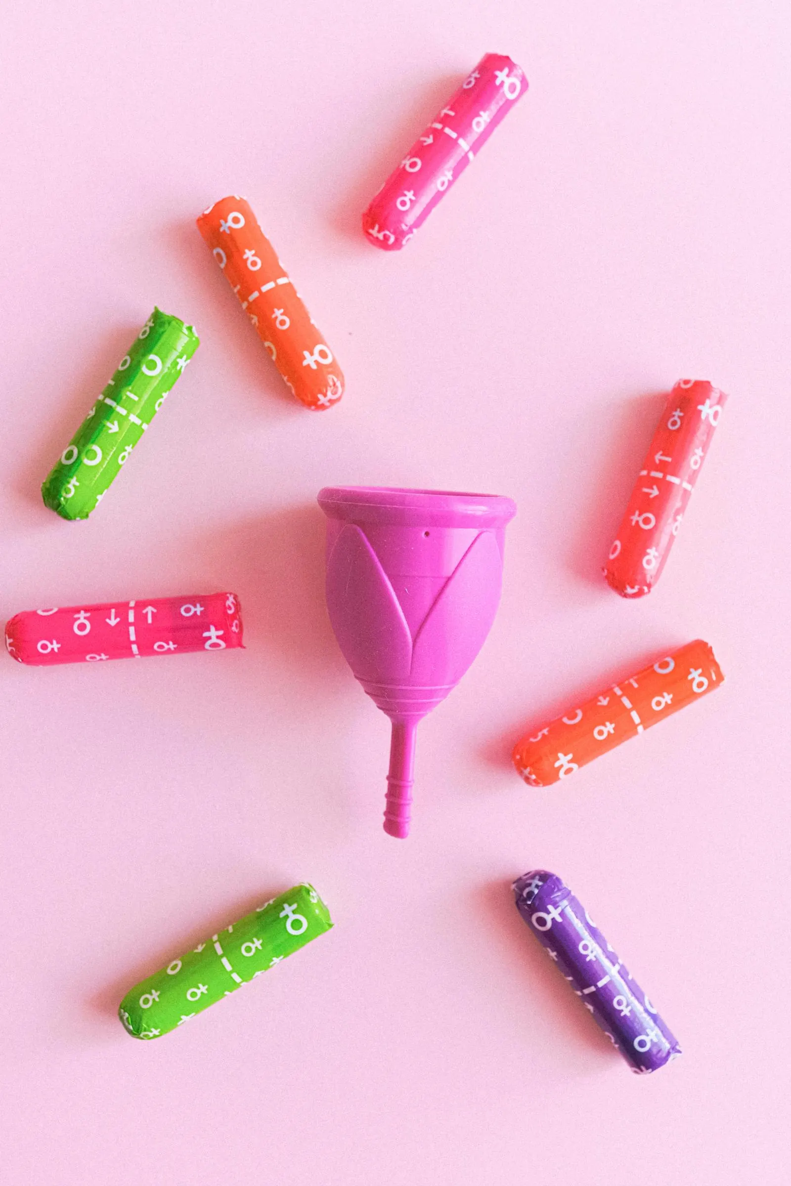 Copo menstrual e tampões sobre fundo rosa